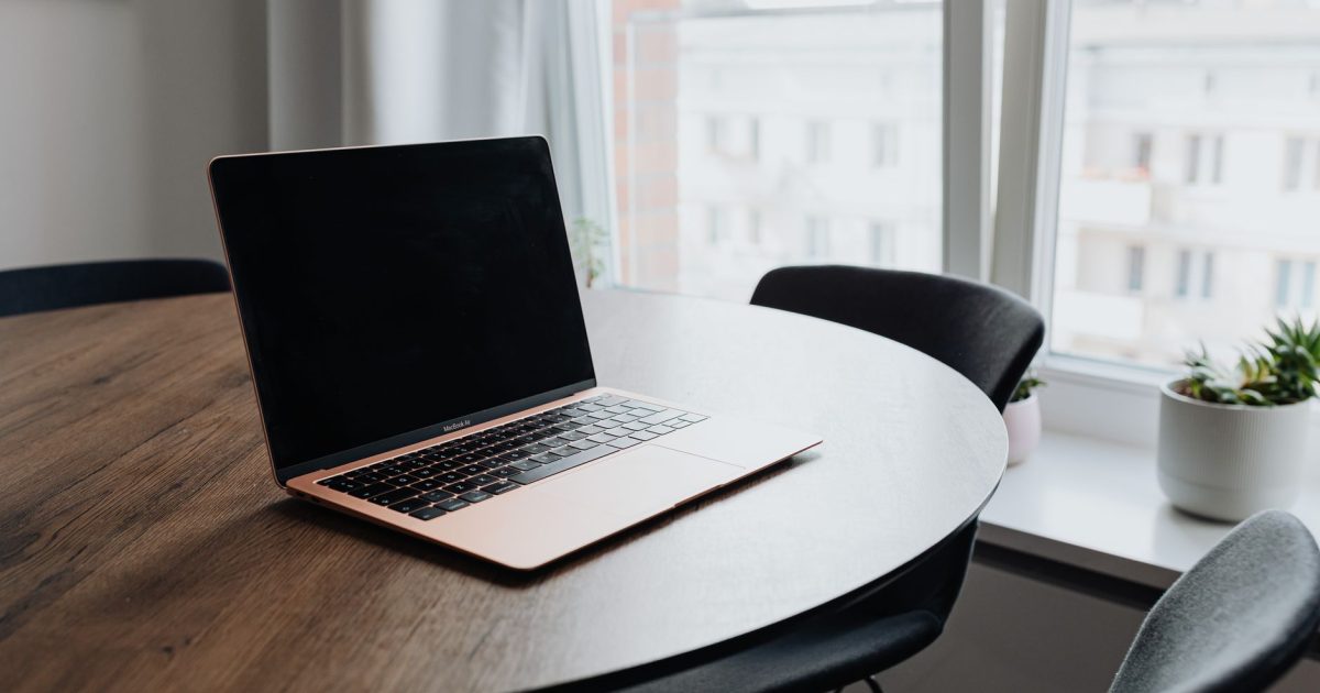 A cozy workspace with a laptop on a wooden table by a window offering natural light.