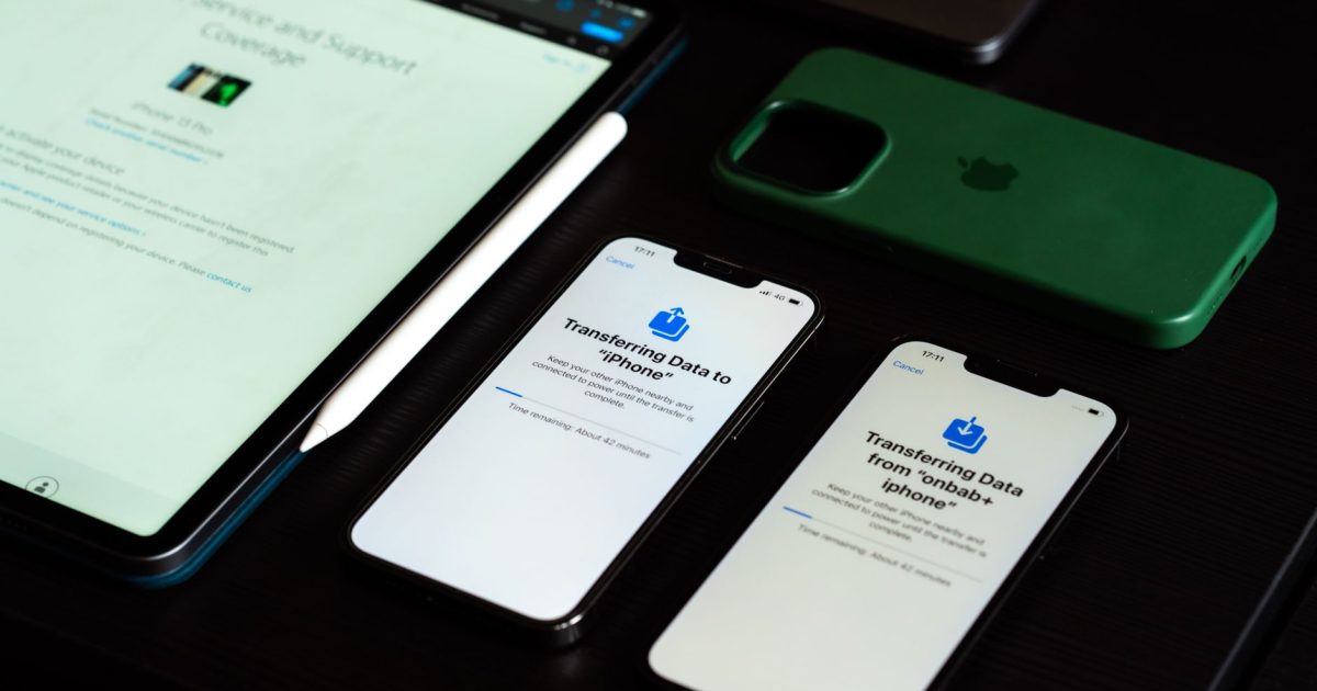 High-angle view of digital devices including iPhones and an iPad on a desk, showcasing data transfer.
