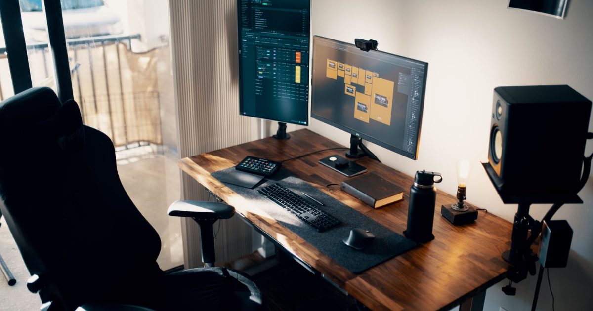 Contemporary office setup with dual monitors, ergonomic chair, and wooden desk.