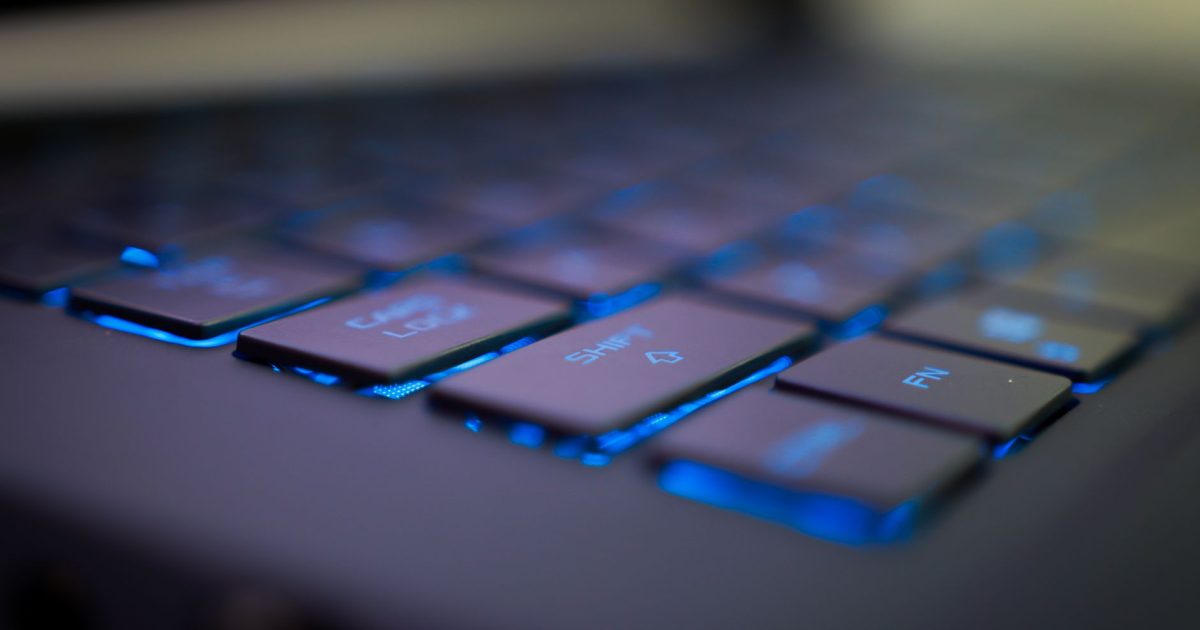 Focused view of a blue illuminated laptop keyboard emphasizing keys and technology.