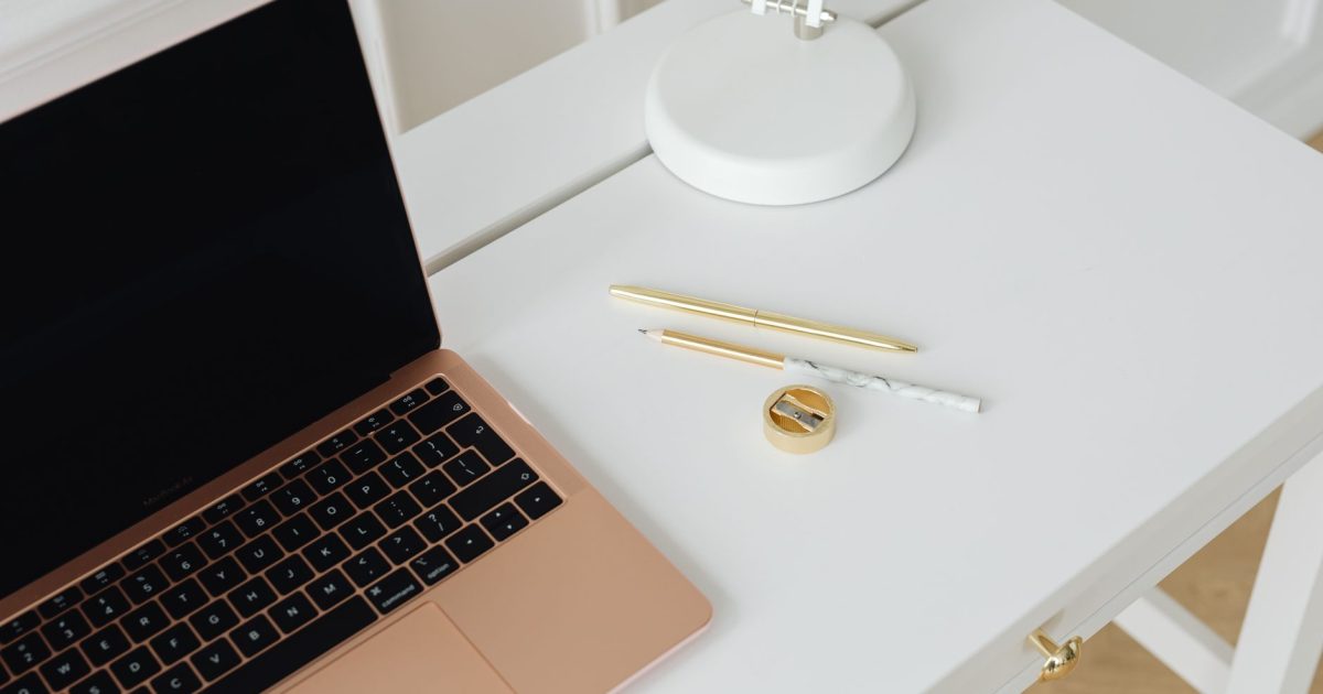 A clean, minimalist desk setup with a laptop, pens, and lamp, perfect for workspaces.