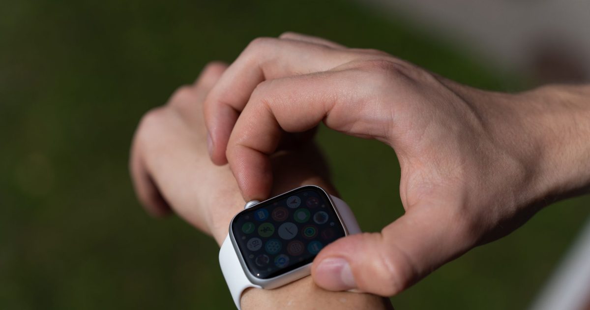 Detailed view of a hand interacting with a smartwatch outdoors.