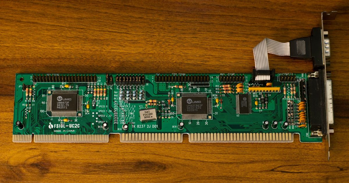 Close-up of a vintage computer circuit board showcasing intricate electronic details on a wooden surface.