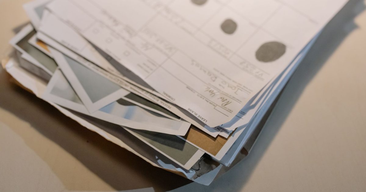 Close-up view of a stack of various papers and documents on a desk surface.