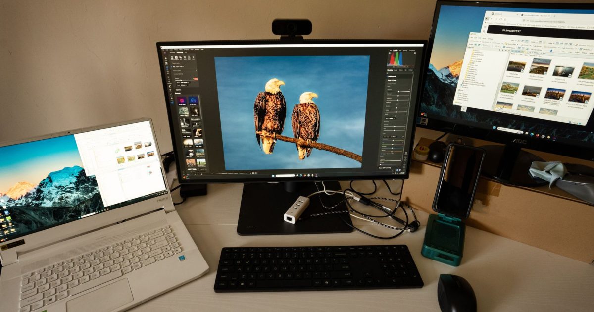 Photographer's workspace with dual monitors, laptop, and editing software.
