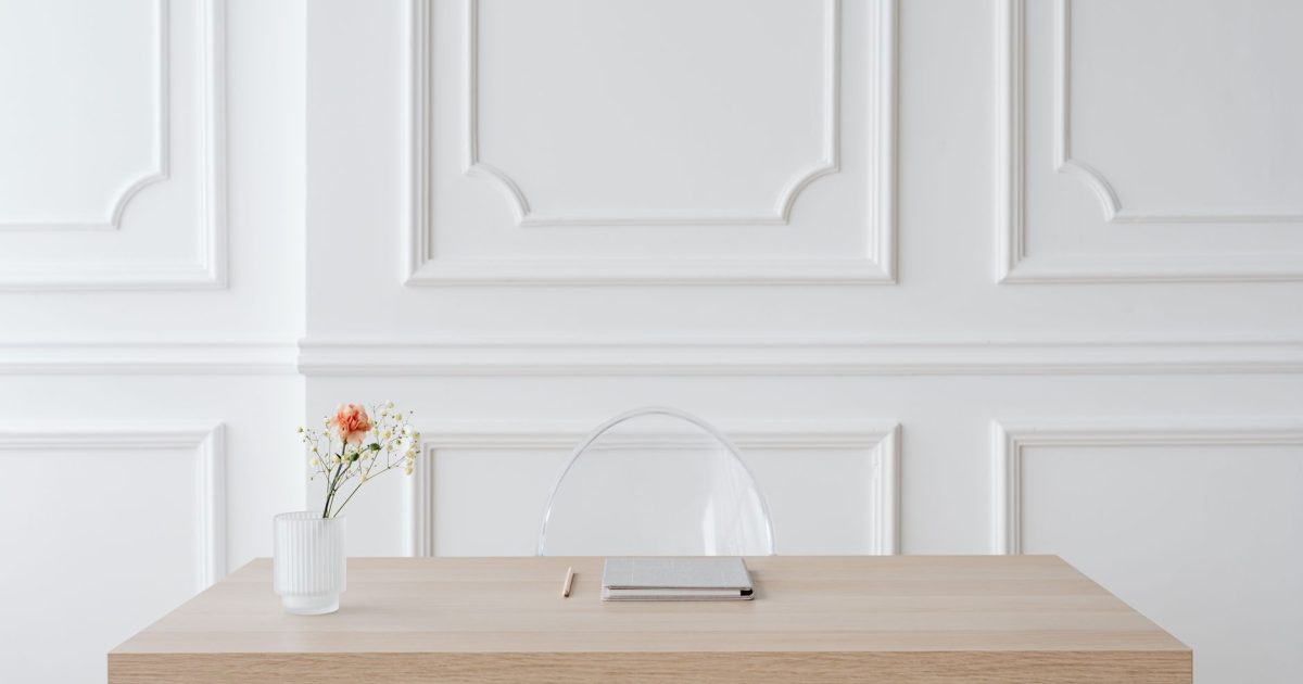 Elegant minimalist workspace with wooden desk, glass vase and panel wall.