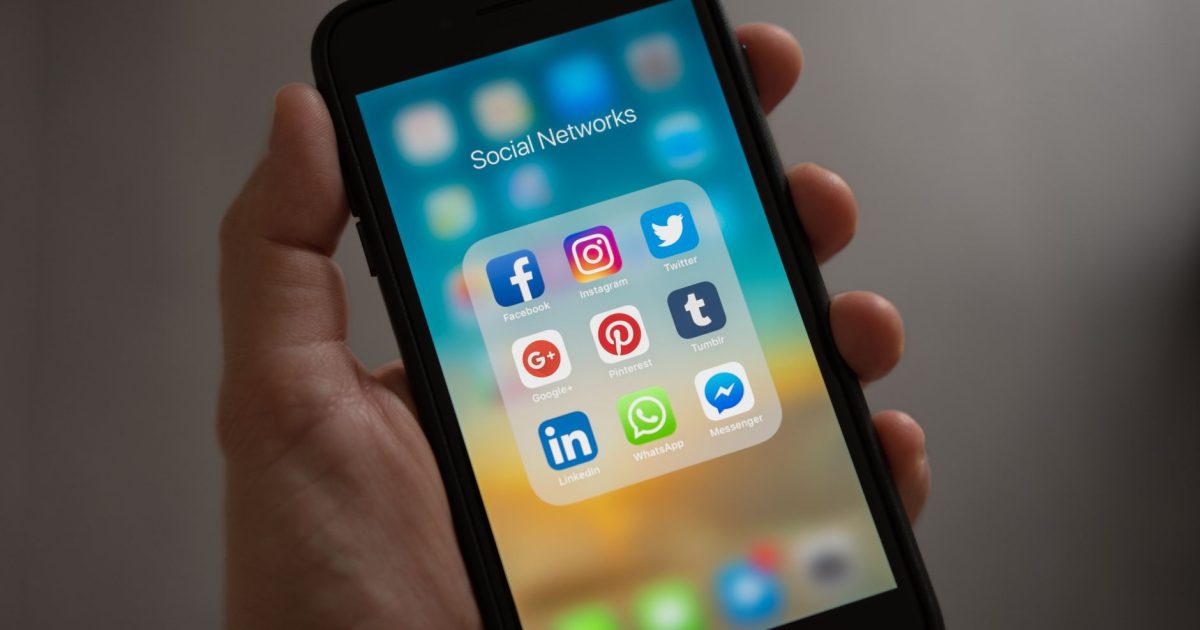 A smartphone displaying various social media icons held in a hand, showcasing modern communication apps.