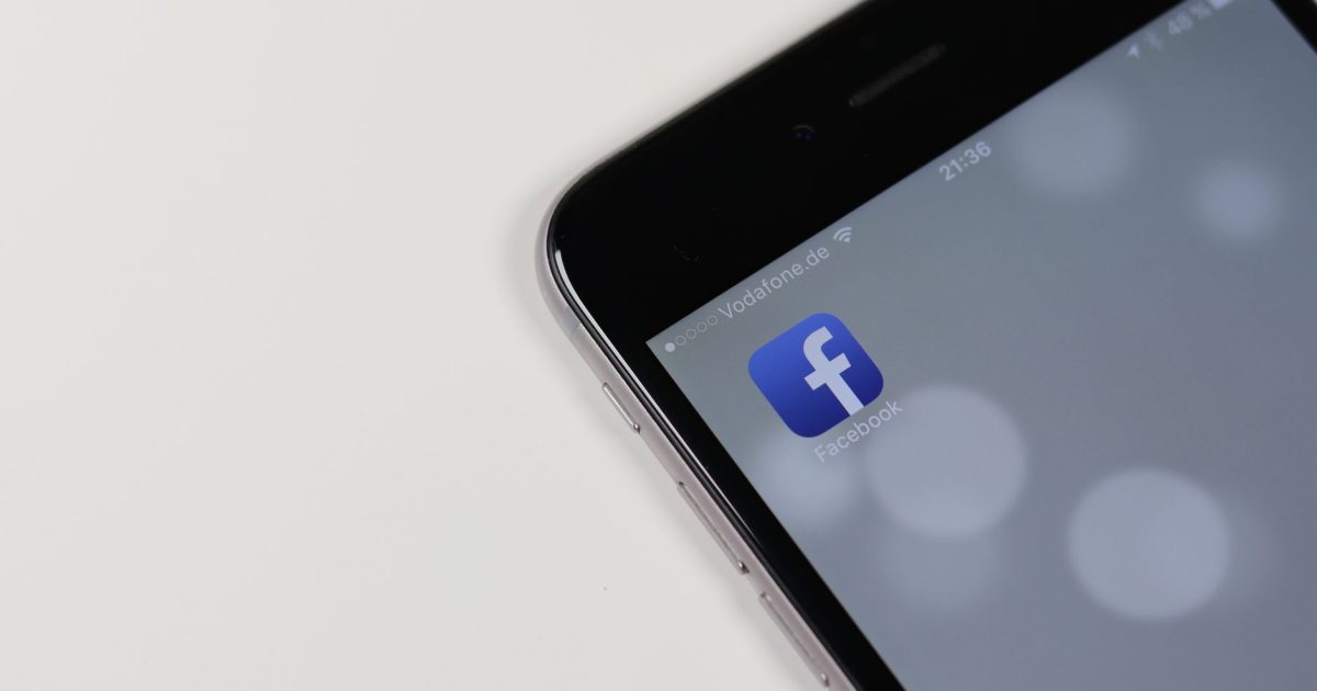 iPhone displaying Facebook app icon with blurred background, emphasizing social media connectivity.