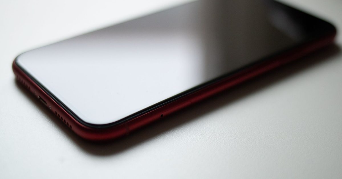 Close-up image of a red smartphone lying on a white surface with a modern sleek design.
