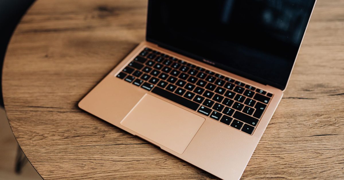Golden laptop on a wooden table, viewed from above, showcasing modern design and sleek aesthetics.