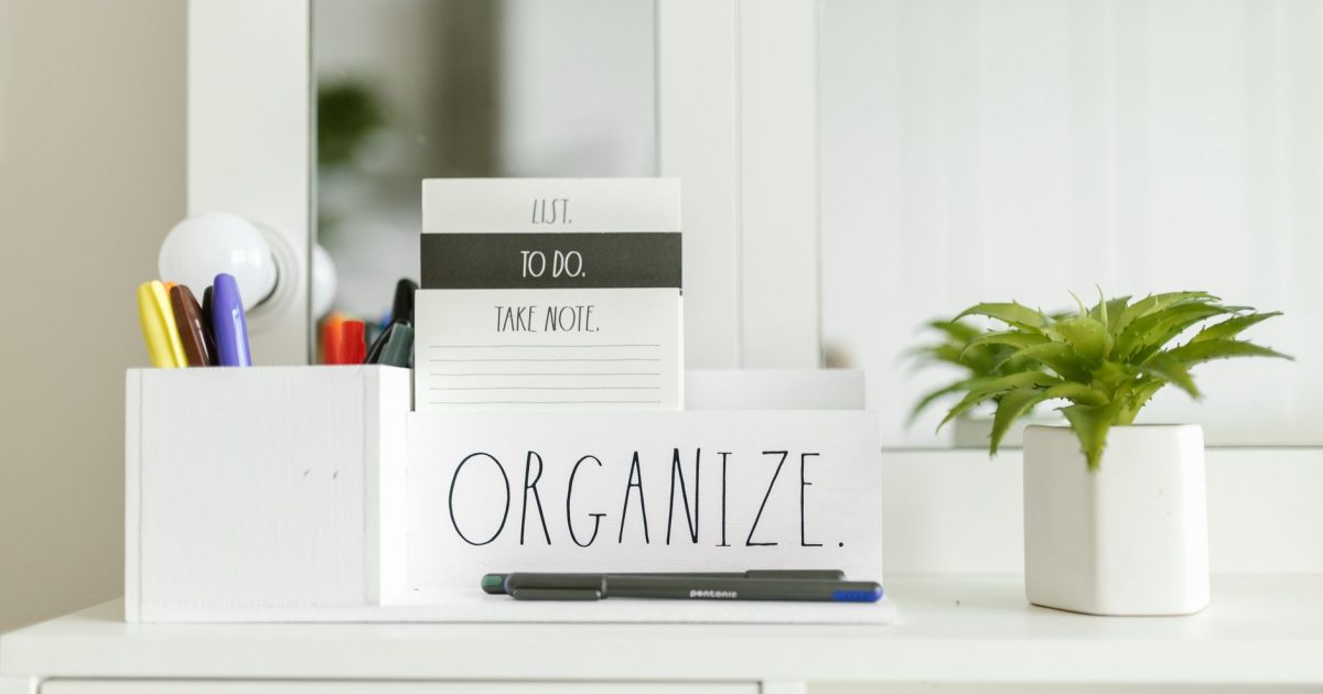 Close-up of an organized workspace featuring a notebook, pen holder, and green plant.