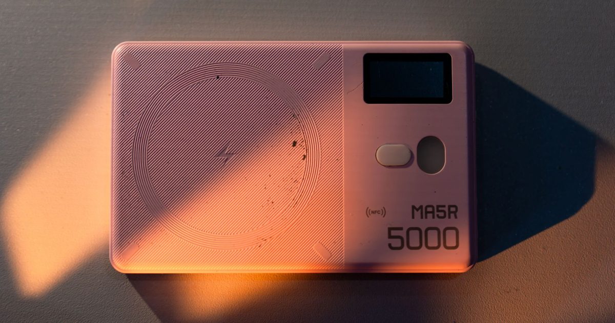 Stylish pink MA5R 5000 power bank with NFC feature in artistic lighting.