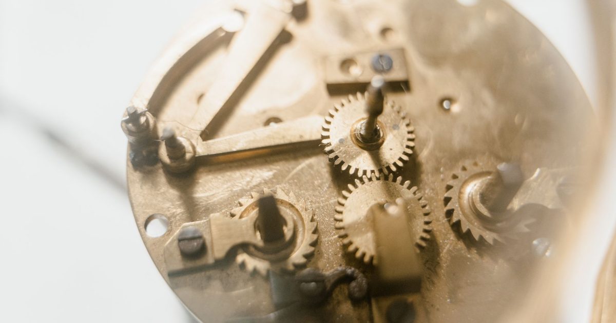 Detailed view of clockwork mechanism showing brass gears and components in soft focus.