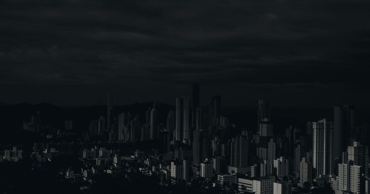 Dark and moody cityscape image showcasing skyscrapers under a cloudy sky.