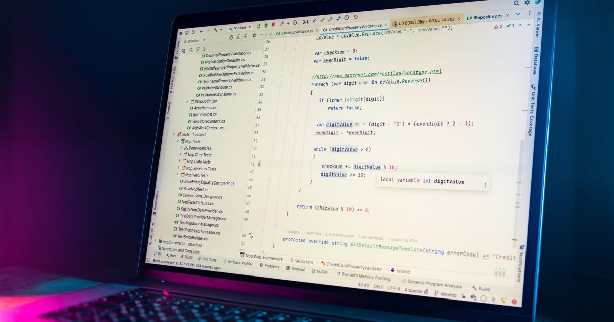 A laptop screen showing a code editor with visible programming code in a dimly lit environment.
